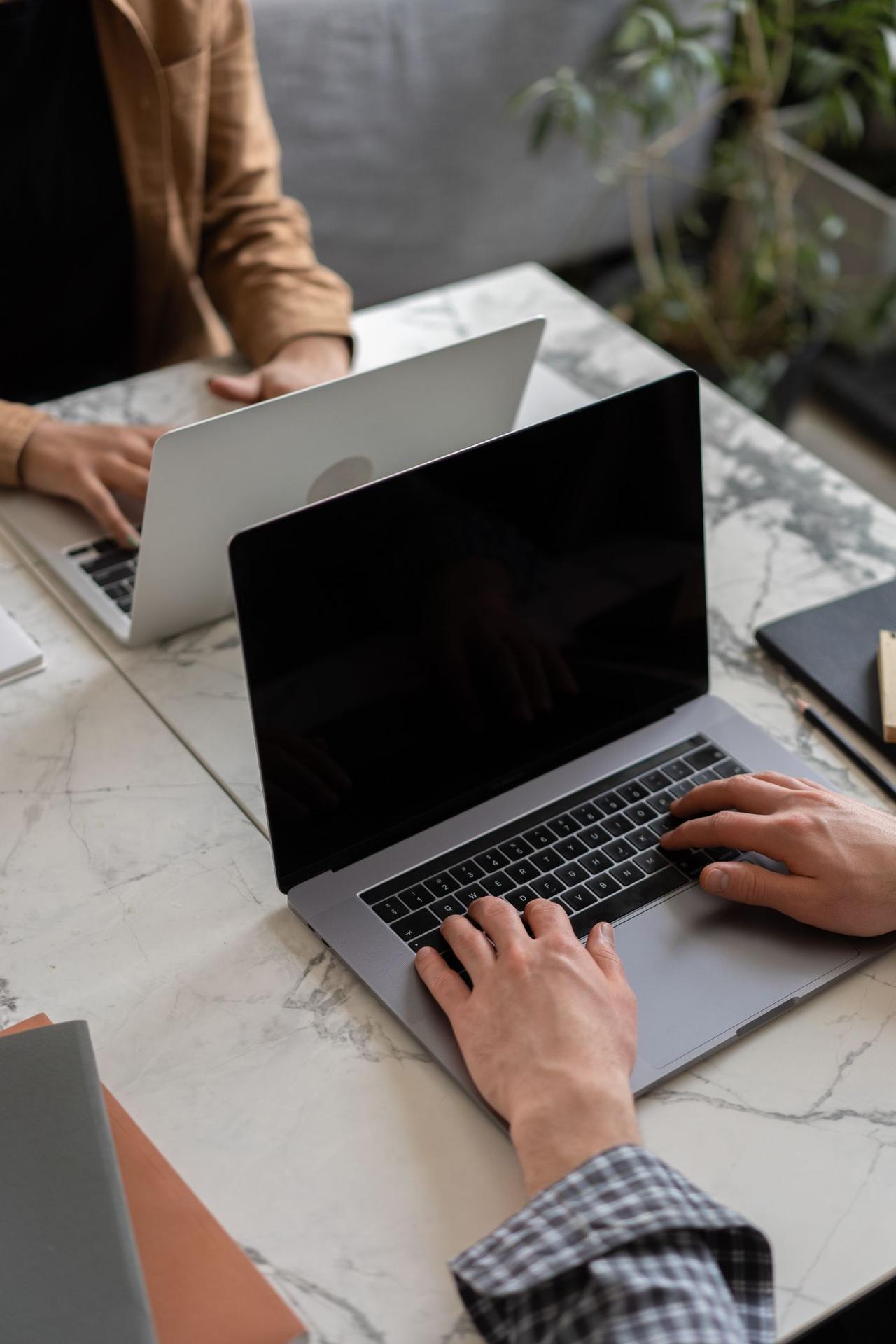 Seseorang membaca artikel informasi di laptop sambil mencatat poin penting