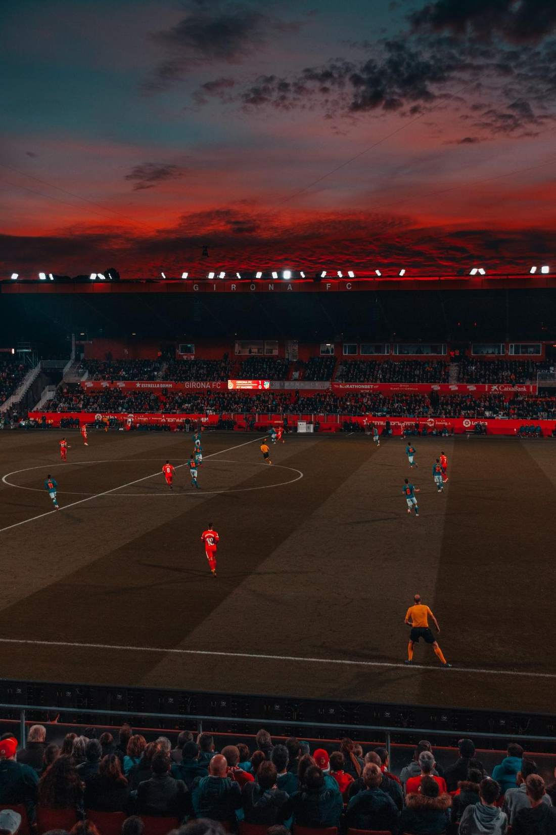 Stadion sepak bola dengan sorot lampu saat pertandingan senja